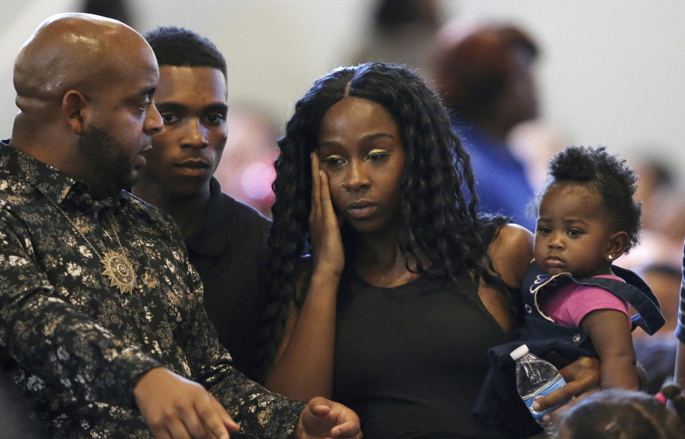 Rev. Jarrett Maupin, left, arrives with Dravon Ames, second from left, Iesha Harper, second from right, and one of the family's two daughters, 1-year-old London, prior to the start of a community meeting, Tuesday, June 18, 2019, in Phoenix. The community meeting stems from reaction to a videotaped encounter that surfaced recently of Ames and his pregnant fiancee, Harper, having had guns aimed at them by Phoenix police during a response to a shoplifting report, as well as the issue of recent police-involved shootings in the community. (AP Photo/Ross D. Franklin)