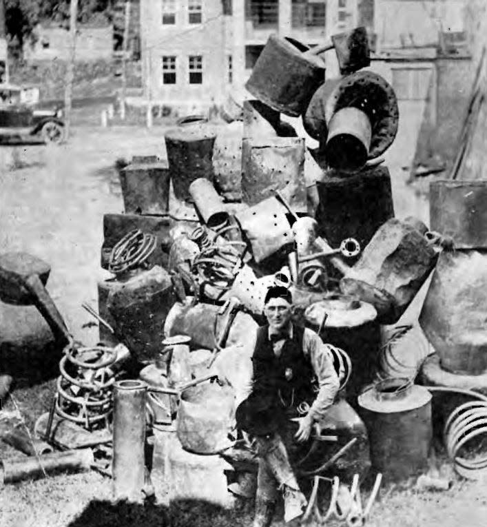 Jesse James Bailey poses with a stack of busted moonshine stills in Madison County.