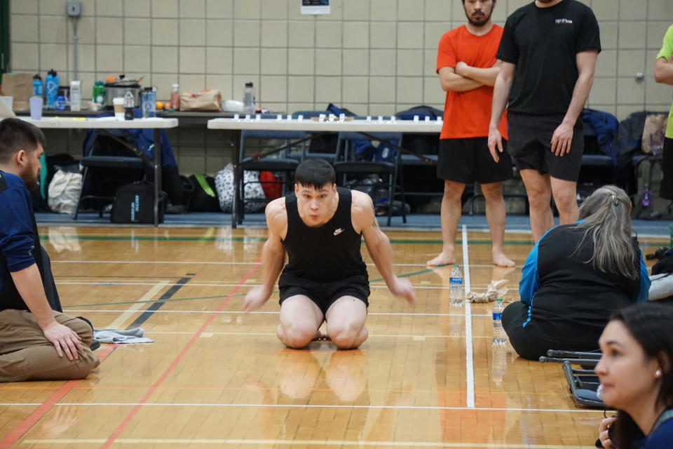 A young athlete prepares to leap forward as he competes on March 14, 2024 in the knee jump, one of the traditional Indigenous sports events staged at the Arctic Winter Games in the Matanuska-Susitna Borough. (Photo by Yereth Rosen/Alaska Beacon)