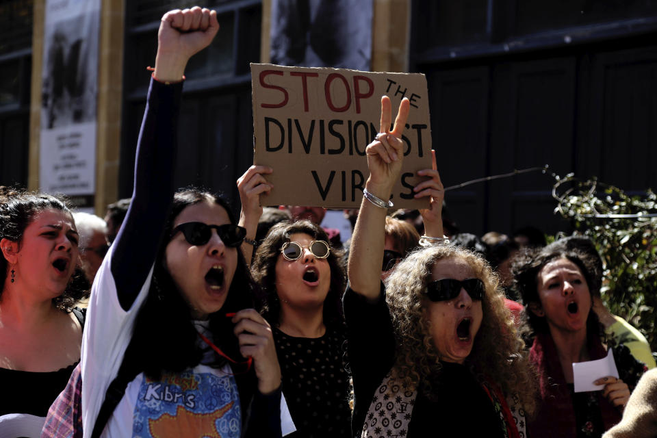 Greek Cypriot demonstrators shout slogans during a protest against a closed crossing point in the ethnically divided capital Nicosia, Cyprus, Saturday, March 8, 2020. Demonstrators staged another protest against a decision by the Cyprus government to temporarily shut four of nine crossing points along a United Nations controlled buffer zone that separates the south from the breakaway Turkish Cypriot north. The Cypriot government says it shut the crossing points to better check for potential coronavirus carriers. (AP Photo/Petros Karadjias)