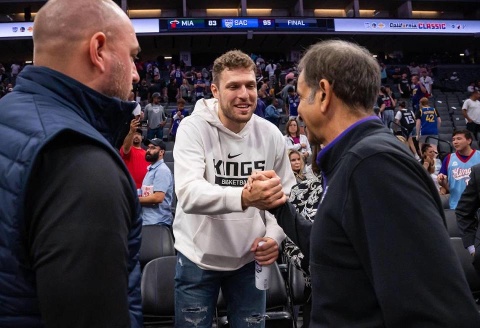 EuroLeague MVP and incoming Sacramento King Sasha Vezenkov shakes hands with owner Vivek Ranadivé, right, after sitting with general manager Monte McNair, left, for most of the California Classic NBA summer league basketball game between the Kings and the Miami Heat in July.