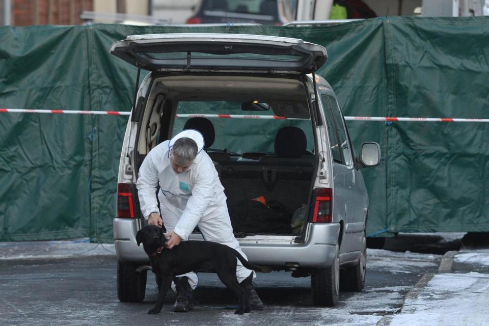 A forensic officer with a dog at the scene of a house fire as five people are questioned (PA Wire/PA Images)