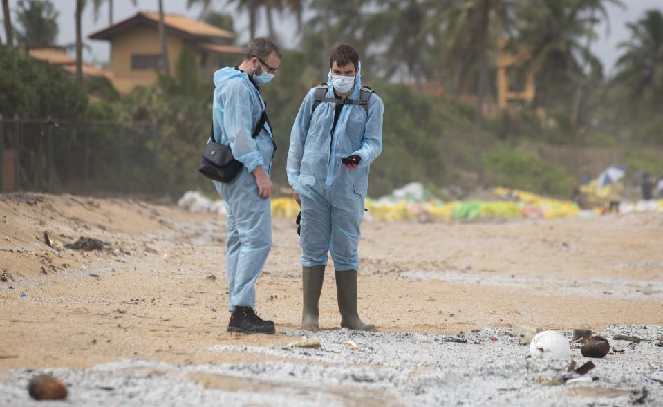 Unidentified foreign investigators inspect debris washed ashore on the beach from the fire-damaged container ship MV X-Press Pearl in Kapungoda, on the out skirts of Colombo, Sri Lanka, Friday, June 4, 2021. Authorities were trying to head off a potential environmental disaster as the Singapore flagged ship that had been carrying chemicals was sinking off of the country's main port. (AP Photo/Eranga Jayawardena)