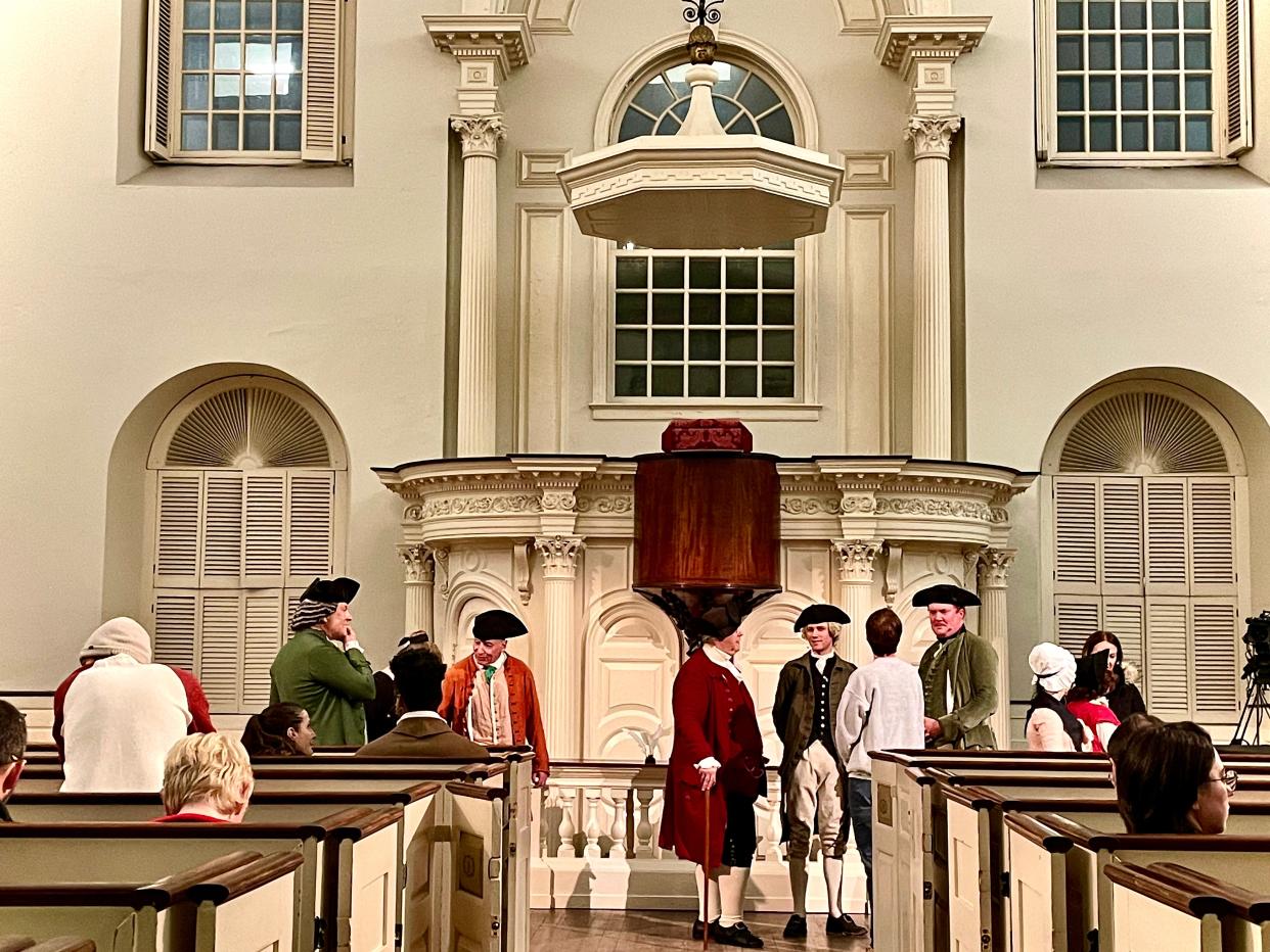 Inside the Old South Meeting House, notable figures from history gather.