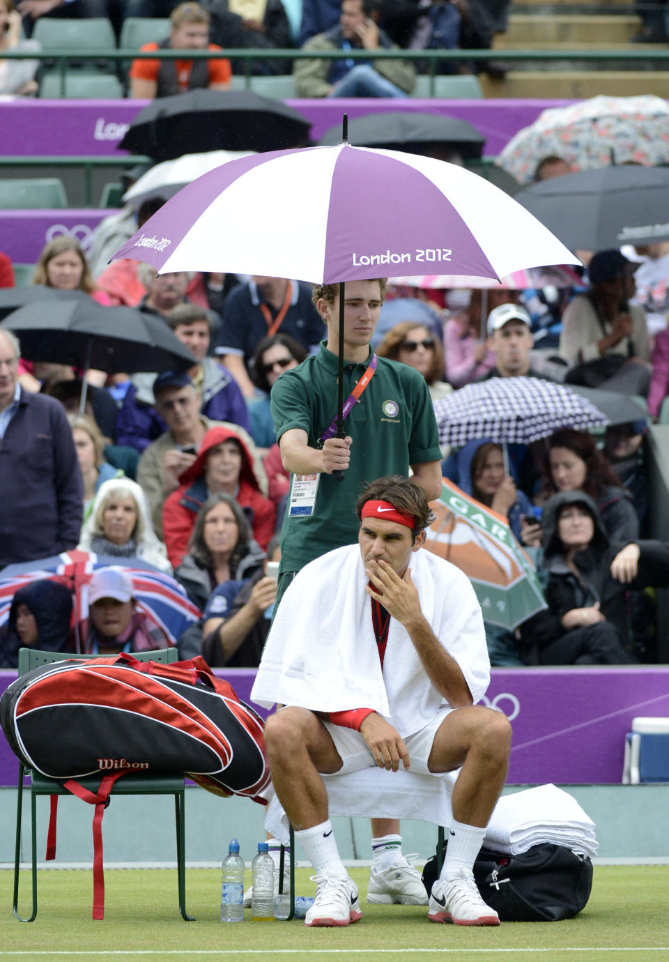 Aug 1, 2012; London, United Kingdom; Roger Federer (SUI) sits under an umbrella as rain delays his match against Denis Istomin (UZB) in the third round of men's tennis during the London 2012 Olympic Games at Basketball Arena. Mandatory Credit: Richard Mackson-USA TODAY Sports