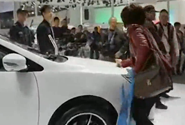 woman scratches car at motor show 