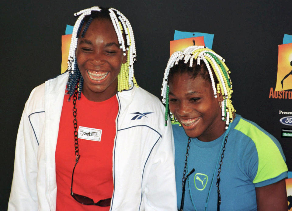 FILE - American tennis players, Venus, left, and Serena Williams smile during a press conference following their match at the Australian Open Tennis Championships in Melbourne, Australia, January 21, 1998. After nearly three decades in the public eye, few can match Serena Williams' array of accomplishments, medals and awards. Through it all, the 23-time Grand Slam title winner hasn't let the public forget that she's a Black American woman who embraces her responsibility as a beacon for her people. (AP Photo/Steve Holland, File)