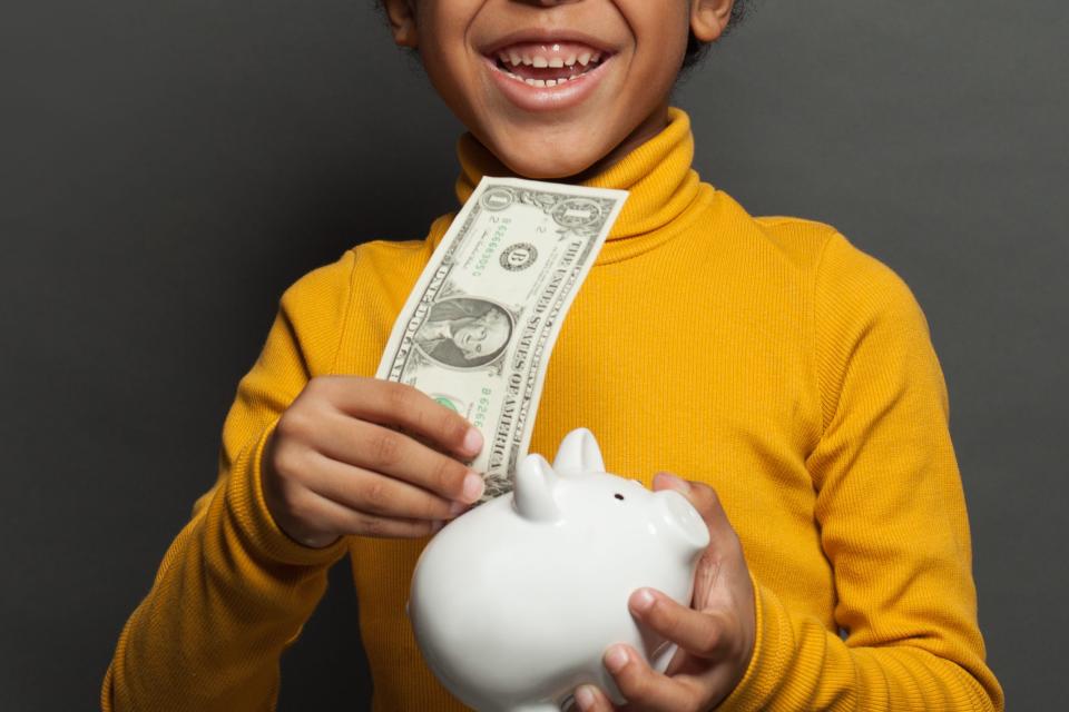 Symbolbild eines Jungen mit einer Dollarnote. - Copyright: JNemchinova | Getty Images