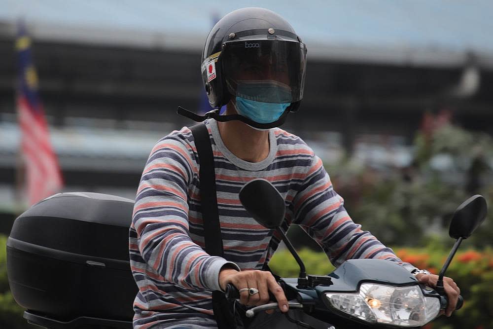 A motorcyclist wears a mask as haze blankets Kuala Lumpur September 18, 2019. — AFP pic