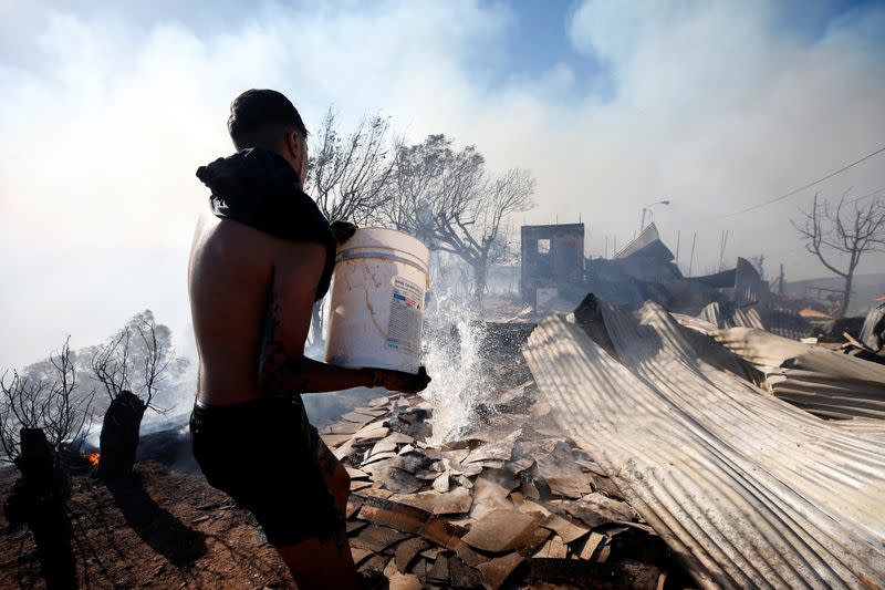 A man throws water to help to extinguish a fire in Valparaiso