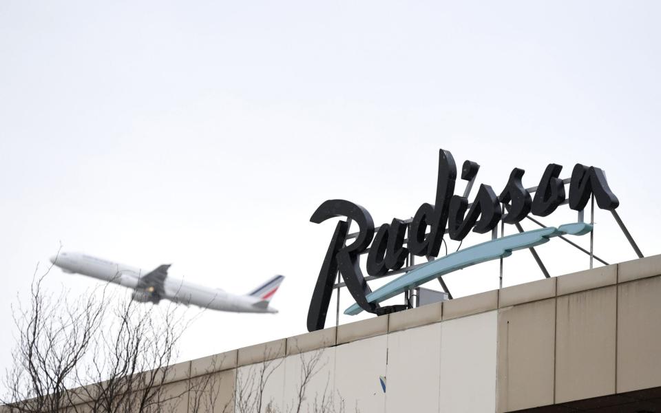 A plane flies past a sign for a Radisson hotel at Heathrow airport in west London  - Daniel Leal-Olivas/AFP