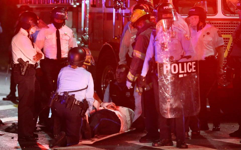 A police officer lies on the ground before being loaded into an ambulance on 52nd Street in West Philadelphia - Tim Tai /The Philadelphia Inquirer 