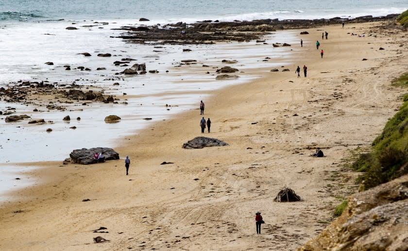 NEWPORT BEACH, CA - MARCH 20, 2020: People walk the beach, but maintain "social distancing" during the coronavirus outbreak at Crystal Cove on March 20, 2020 in Newport Beach, California. (Gina Ferazzi/Los AngelesTimes)