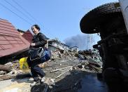 A local resident bring his son's school bags from a collaped house in Tagajo, Miyagi prefecture. Japan raced to avert a meltdown of two reactors at a quake-hit nuclear plant Monday as the death toll from the disaster on the ravaged northeast coast was forecast to exceed 10,000