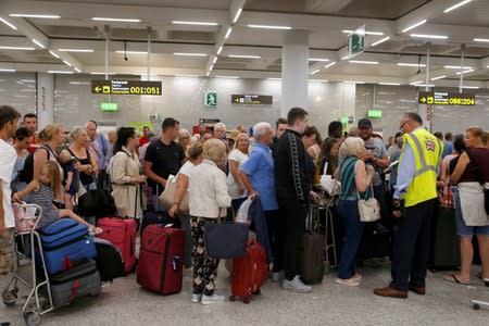 Passengers are seen at Thomas Cook check-in points at Mallorca Airport after the world's oldest travel firm collapsed, in Palma de Mallorca