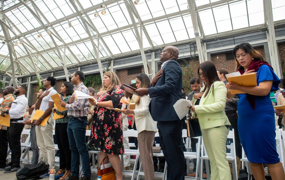 Newly naturalized citizens say the Pledge of Allegiance during a ceremony Wednesday at the New England Botanic Garden at Tower Hill in Boylston.