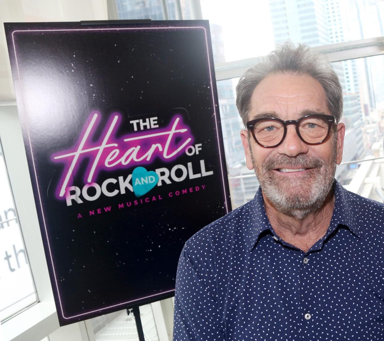 Huey Lewis standing in front of a sign for his musical