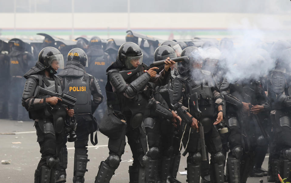 A police officer fires a projectile during a rally against a controversial bill on job creation in Jakarta, Indonesia, Thursday, Oct. 8, 2020. Thousands of enraged students and workers staged rallies across Indonesia on Thursday in opposition to the new law they say will cripple labor rights and harm the environment. (AP Photo/Tatan Syuflana)