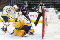 Columbus Blue Jackets' Jack Roslovic, top, scores a goal against Nashville Predators' Juuse Saros, front, as Alexandre Carrier defends during the second period of an NHL hockey game Wednesday, May 5, 2021, in Columbus, Ohio. (AP Photo/Jay LaPrete)