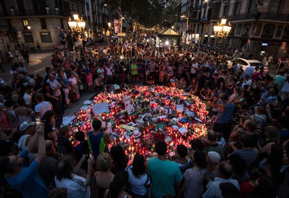 People gather around tributes laid on Las Ramblas near to the scene of the terrorist attack in Barcelona (Getty)