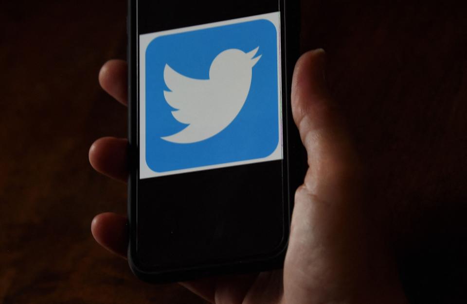 a Twitter logo is displayed on a mobile phone.