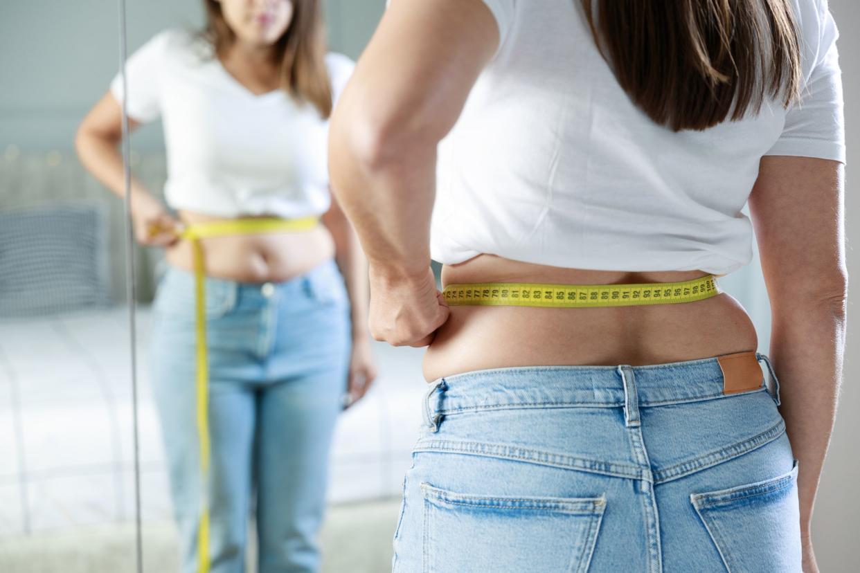 Young woman taking measurements of her body