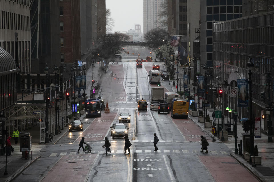 Commuters cross 42nd Street in front of Grand Central Terminal during morning rush hour, Monday, March 23, 2020, in New York. Gov. Andrew Cuomo has ordered most New Yorkers to stay home from work to slow the coronavirus pandemic. (AP Photo/Mark Lennihan)