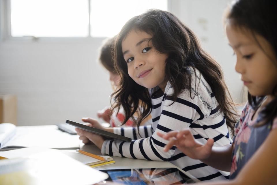 Girls sit a table working on touchscreen tablets.