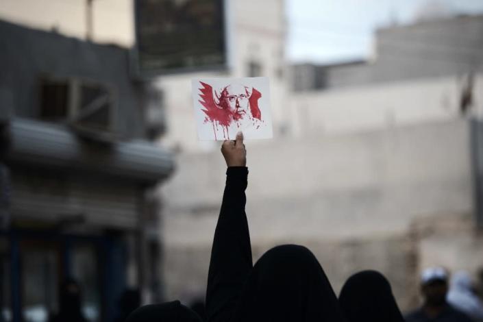 A Bahraini woman holds a placard bearing a portrait of prominent Shiite cleric Nimr al-Nimr during a protest in the village of Jidhafs, on January 2, 2016 (AFP Photo/Mohammed Al-Shaikh)