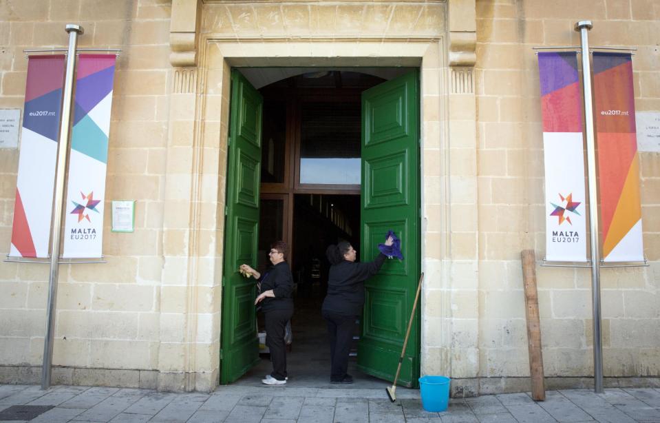 Two women clean a door at the Mediterranean Conference Center ahead of an EU summit meeting in Valletta, Malta, on Thursday, Feb. 2, 2017. European foreign policy chief Federica Mogherini said that Friday's summit on migration is poised to take a big step in closing off the illegal migration route through the central Mediterranean where thousands have died over the past years trying to reach the EU from Libya. (AP Photo/Virginia Mayo)