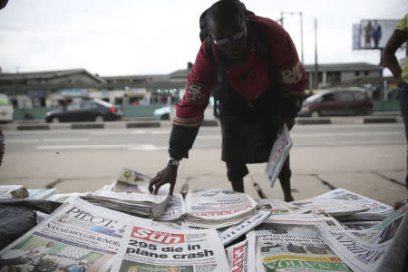 A man arranges newspapers at a vendor's stand along a road in Ikoyi district in Lagos July 18, 2014. REUTERS/Akintunde Akinleye