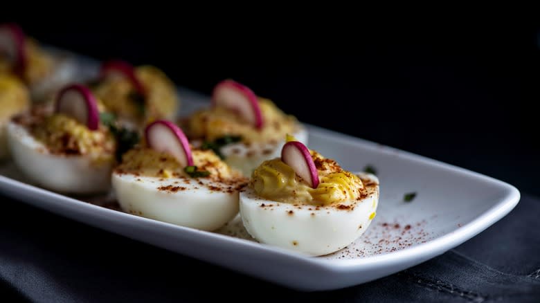 Deviled eggs garnished with smoked paprika and radish