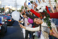 People wave flowers as they gather to protest against the results of the country's presidential election in Minsk, Belarus, Thursday, Aug. 13, 2020. Crowds of protesters in Belarus swarmed the streets and thousands of workers rallied outside industrial plants to denounce a police crackdown on demonstrations over a disputed election that extended the 26-year rule of authoritarian President Alexander Lukashenko. (AP Photo/Sergei Grits)