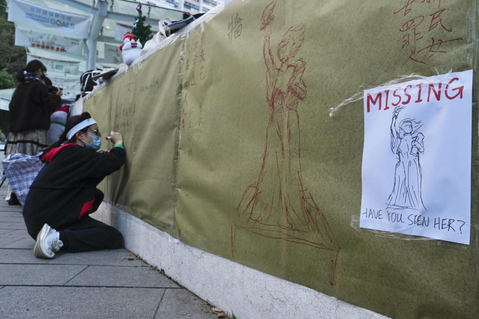 A university student writes notes at the site after the "Goddess of Democracy" statue, a memorial for those killed in the 1989 Tiananmen crackdown, was removed at the University of Hong Kong Friday, Dec. 24, 2021. The Chinese University of Hong Kong early Friday morning took down the statue based on a figure created by art students and brought to the square shortly before the crackdown in which hundreds of people were killed. (AP Photo/Vincent Yu)