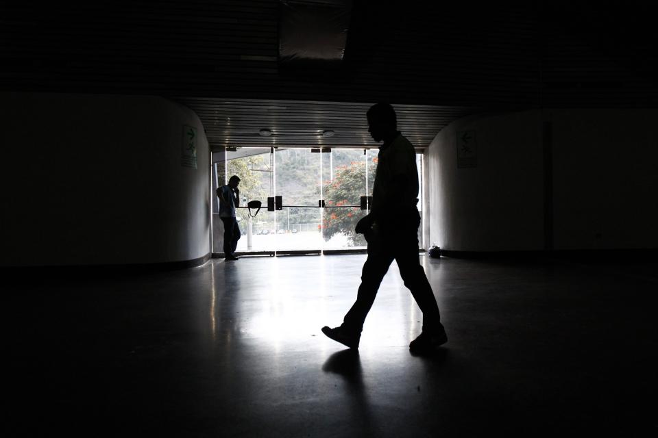 A security guard walks past an exit door as he waits for the power to return after a blackout during the FIBA Americas Championship basketball game between Paraguay and Dominican Republic in Caracas