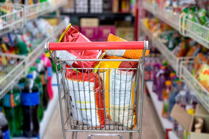 Snacks in a grocery cart in the supermarket aisle.