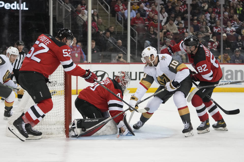 New Jersey Devils goaltender Vitek Vanecek (41), defenseman Santeri Hatakka (82) and defenseman Cal Foote (52) tend the net against Vegas Golden Knights center Nicolas Roy (10) during the first period of an NHL hockey game, Monday, Jan. 22, 2024, in Newark, N.J. (AP Photo/Mary Altaffer)