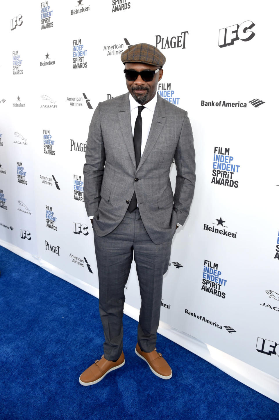 Idris Elba in a gray suit and wool cap at the 2016 Film Independent Spirit Awards on February 27, 2016 in Santa Monica, California.