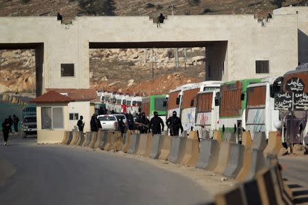 Fighters from a coalition of rebel groups called "Jaish al Fatah", also known as "Army of Fatah" (Conquest Army), secure the area while buses evacuating fighters and civilians from the two besieged Shi'ite towns of al-Foua and Kefraya in the mainly rebel-held northwestern province of Idlib, arrive at the Syrian-Turkish border crossing of Bab al-Hawa, December 28, 2015. REUTERS/Khalil Ashawi