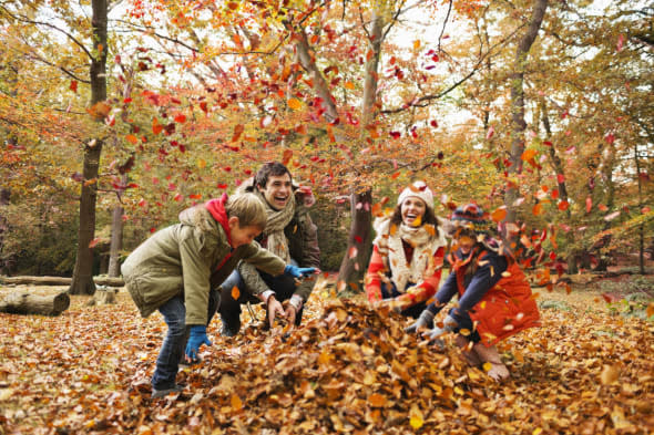 Family playing in autumn leaves