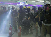 Demonstrators stand amid haze from fire extinguishers during a protest at the Yuen Long MTR station in Hong Kong, Wednesday, Aug. 21, 2019. Hong Kong riot police faced off with protesters occupying a suburban train station Wednesday evening following a commemoration of a violent attack there by masked assailants on supporters of the anti-government movement. (AP Photo/Kin Cheung)