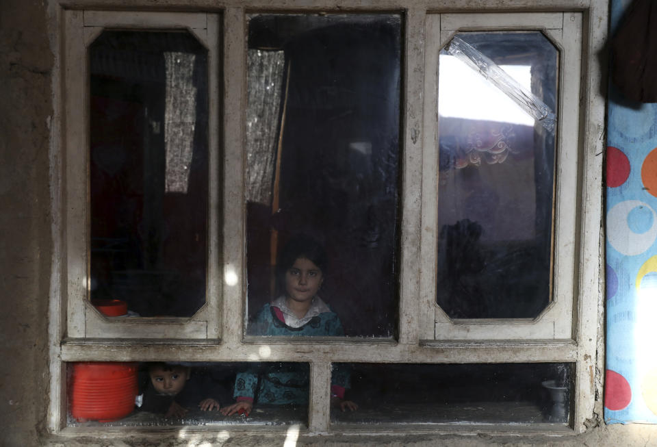 An internally displaced sister and brother pose for a photograph inside their temporary home in the city of Kabul, Afghanistan, Wednesday, Dec. 30, 2020. Save the Children has warned that more than 300,000 Afghan children face freezing winter conditions that could lead to illness, in the worst cases death, without proper winter clothing and heating (AP Photo/Rahmat Gul)