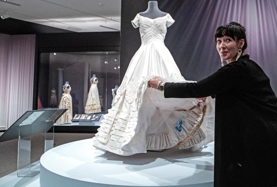 Katya Roelse, a University of Delaware fashion and apparel studies professor, shows the blue bow on the petticoat trim, the "something blue," on a replica of Ann Lowe's wedding dress worn by Jacqueline Bouvier in her wedding to John F. Kennedy, during a media preview of the "Ann Lowe: American Couturier" exhibition at the Winterthur Museum, Garden and Library near Centreville on Wednesday, Aug. 30, 2023. The exhibit features nearly 40 gowns, including some that have never been on display, and runs from Sept. 9 to Jan. 7, 2024.