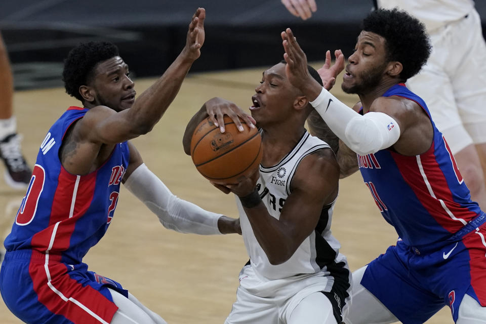 San Antonio Spurs guard Lonnie Walker IV, center, is pressured by Detroit Pistons guard Josh Jackson, left, and forward Saddiq Bey, right, during the second half of an NBA basketball game in San Antonio, Thursday, April 22, 2021. (AP Photo/Eric Gay)