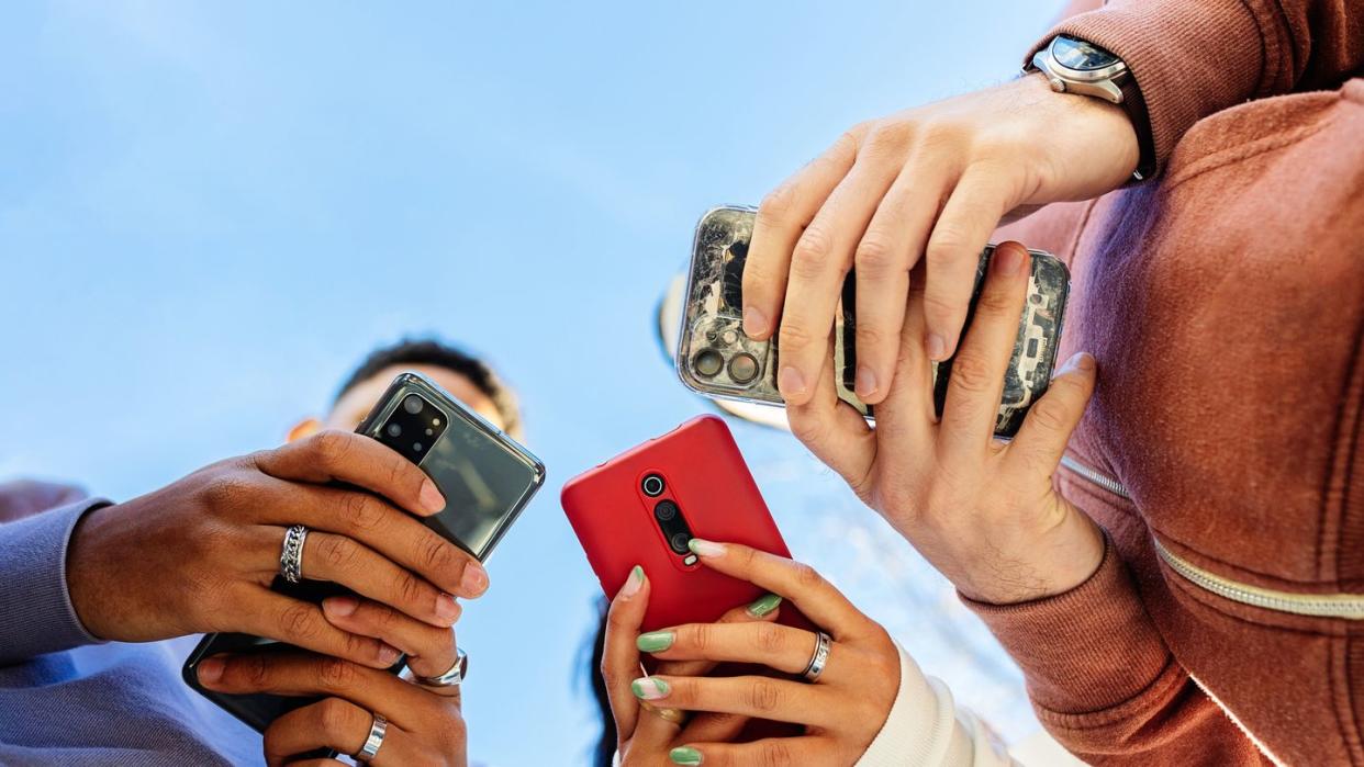 low angle view of three young people using smartphones outdoors