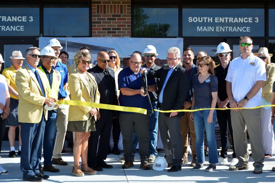 Columbia Public Schools former Chief Operations Officer Randy Gooch, center, cuts the ribbon on the expansion of Columbia Area Career Center. Gooch announced his retirement last year.