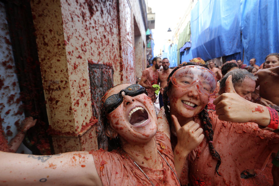 Women react as they throw tomatoes at each other during the annual “Tomatina”, tomato fight fiesta, in the village of Bunol near Valencia, Spain, Wednesday, Aug. 30, 2023. Thousands gather in this eastern Spanish town for the annual street tomato battle that leaves the streets and participants drenched in red pulp from 120,000 kilos of tomatoes. (AP Photo/Alberto Saiz)