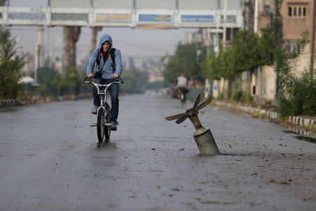 A resident rides his bicycle near what activists said was an exploded cluster bomb shell in the town of Douma, eastern Ghouta in Damascus November 5, 2015. REUTERS/Bassam Khabieh