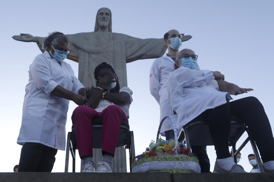 CORRECTS DATE FROM 28 TO 18 - Terezinha da Conceicao, sitting left, and Dulcinea da Silva Lopes, sitting right, become the first women to receive the COVID-19 vaccine produced by China's Sinovac Biotech Ltd, during the start of the vaccination program in front of the Christ the Redeemer statue in Rio de Janeiro, Brazil, Monday, Jan. 18, 2021. (AP Photo/Bruna Prado)