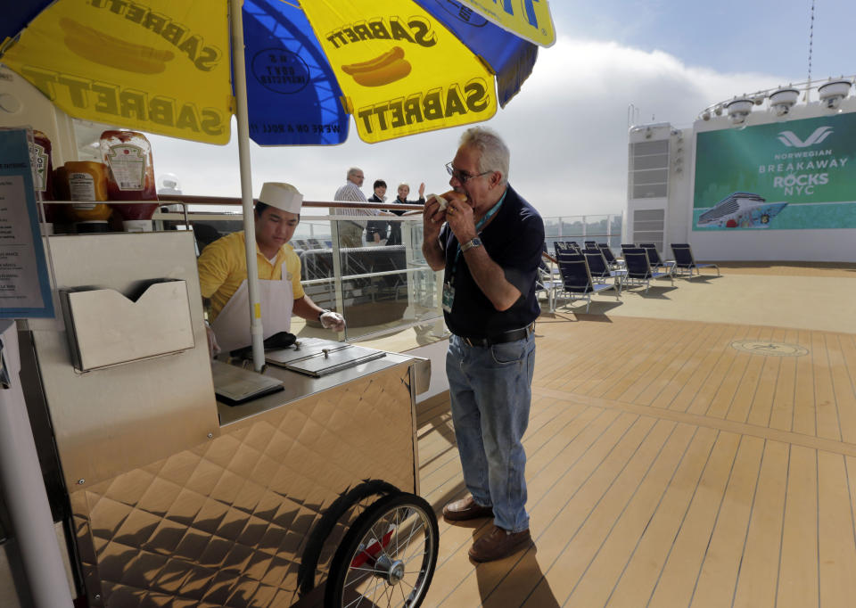 Cary Gilbert, right, of North Brunswick, N.J., eats a hotdog from a New York style cart aboard the Norwegian Cruise Line's new ship, Norwegian Breakaway, which was christened on the Hudson River. in New York, Wednesday, May 8, 2013. The ship is themed on New York City, with a colorful mural on the exterior hull design by pop artist Peter Max featuring the city skyline and the Statue of Liberty. (AP Photo/Richard Drew)